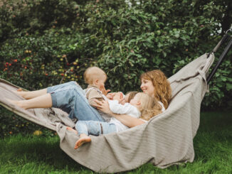 mother with children having fun in a hammock. Mom and kids in a hammock. The family spends time with the children in the garden.