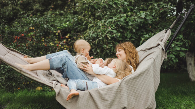 mother with children having fun in a hammock. mother with children having fun in a hammock. Mom and kids in a hammock. The family spends time with the children in the garden.